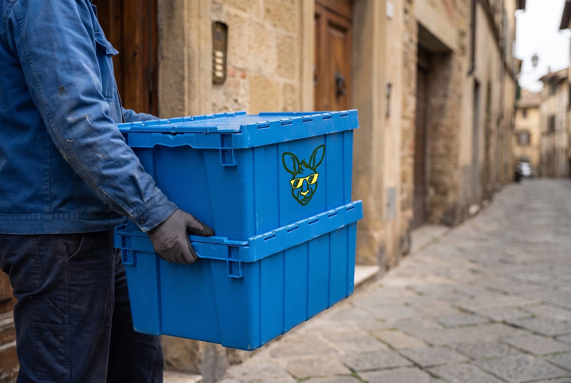 Corriere che porta due Cangubox impilate verso il portone di un palazzo